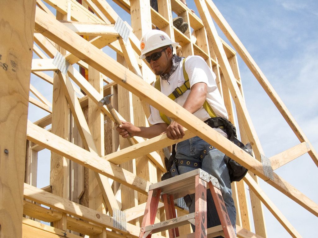 Trabajador con casco y arnés anticaídas trabajando en altura sobre una estructura