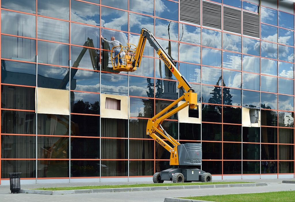 Plataforma de brazo articulado trabajando en una fachada de cristal