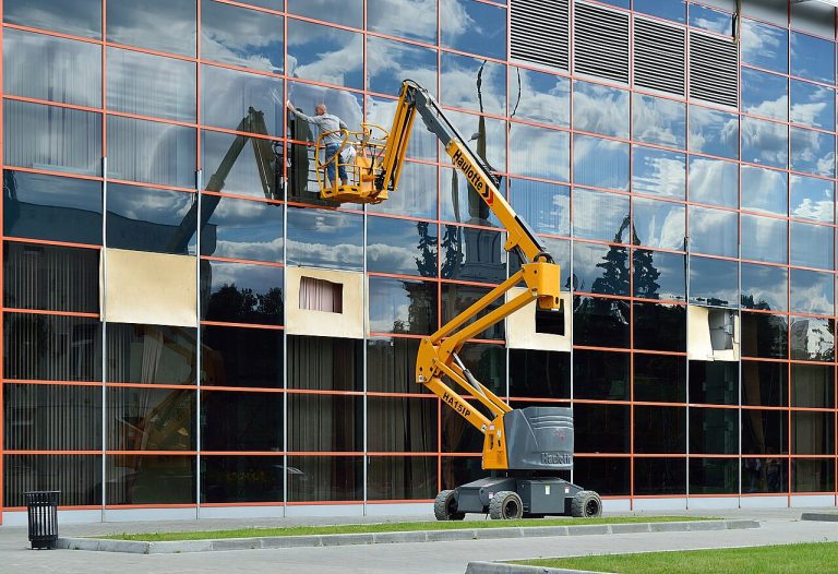 Plataforma de brazo articulado trabajando en una fachada de cristal