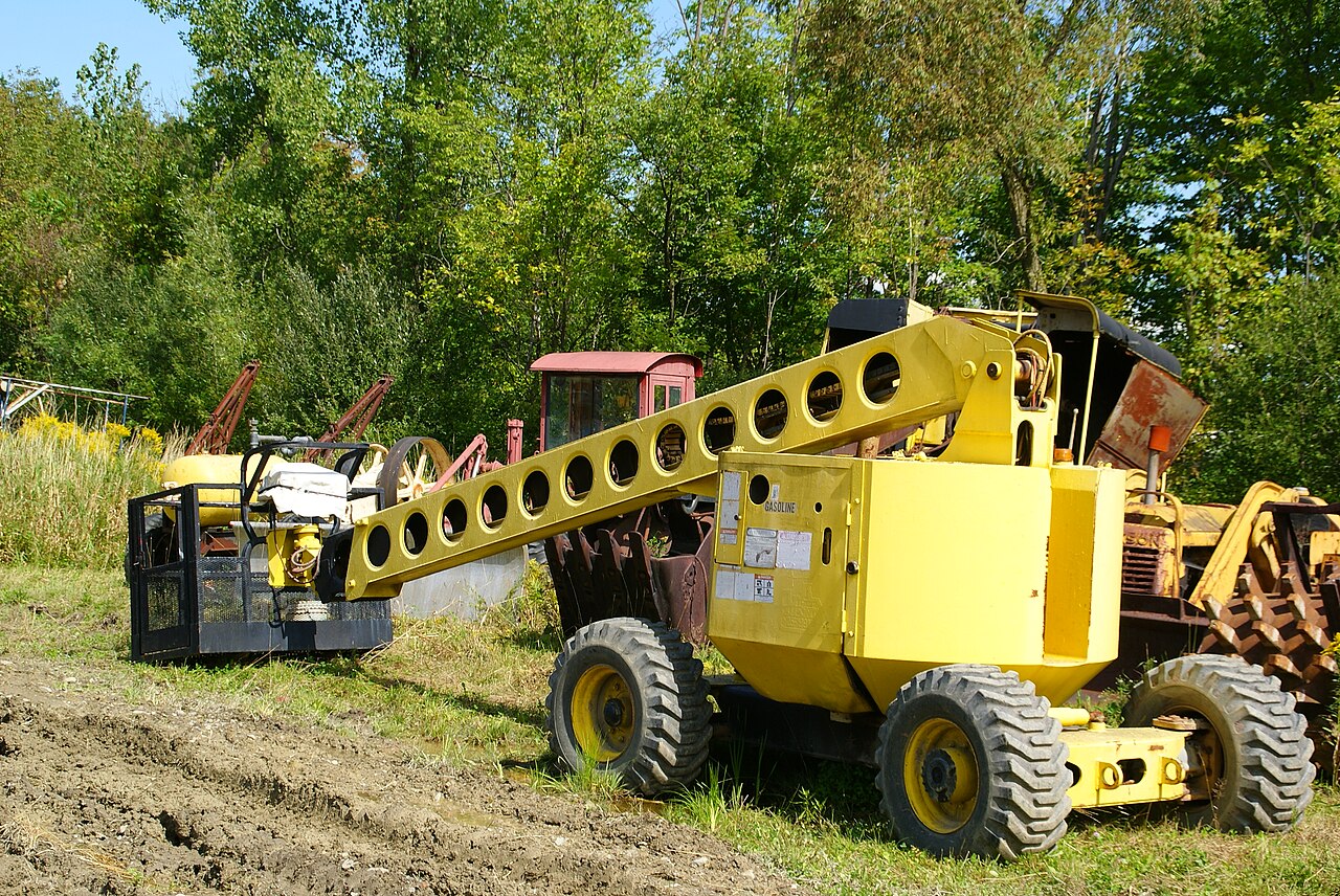 Plataforma elevadora de brazo articulado amarilla con la cesta a un lado