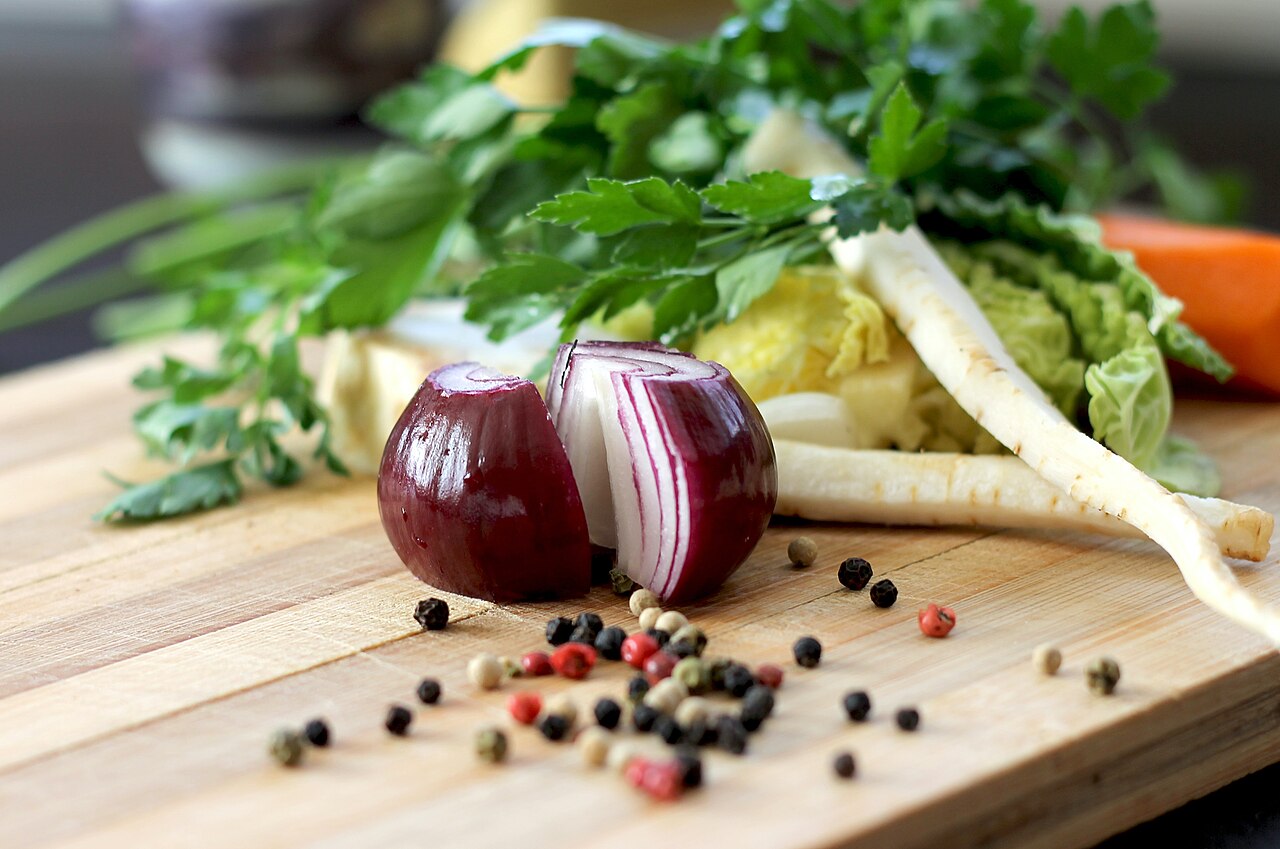 Cebolla, perejil y verduras sobre una tabla de madera